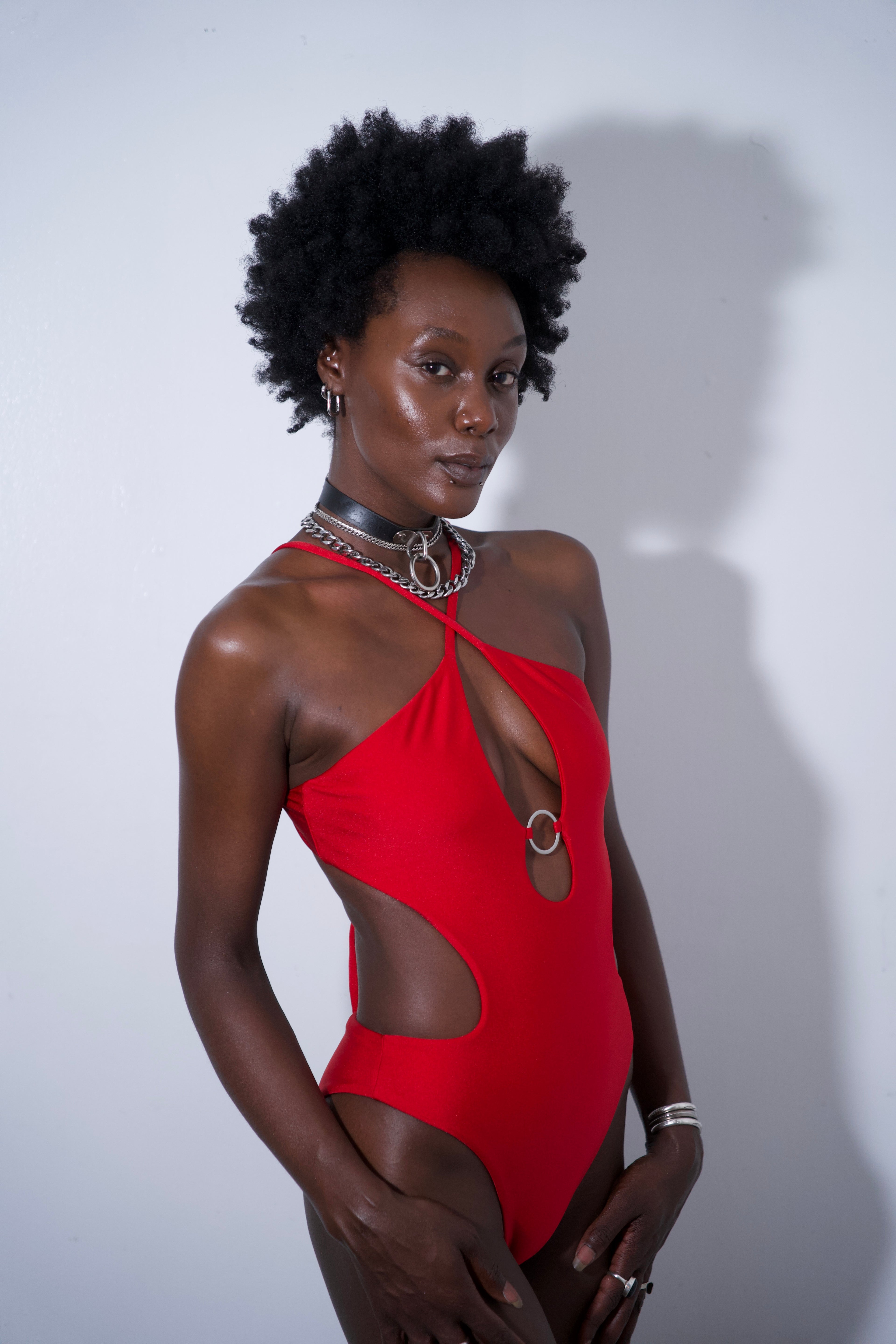 Model wearing Stella One-piece Red swimsuit with cutout details and high-cut legs, showcasing adjustable tie-back closure.