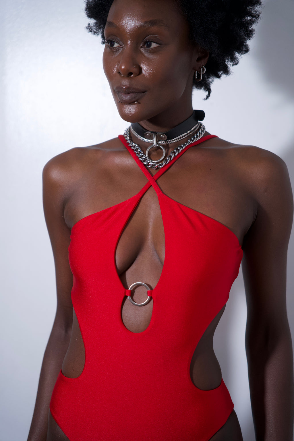 Stella One-piece Red featuring a metal ring and cutout details on a model against a plain background.