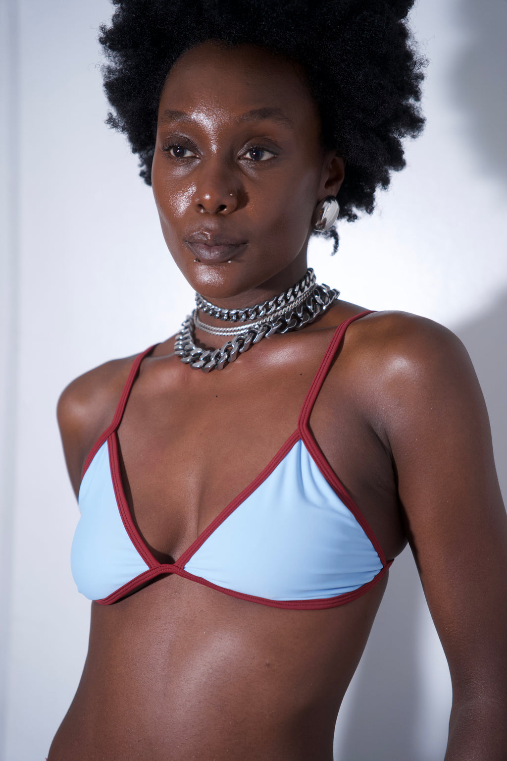 Sandy Bikini Top Blue featuring light blue fabric with red trim and adjustable straps, modeled by a person.