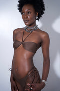 Model wearing the Daphne Bikini Top, a brown bandeau bikini with removable halter strap and stylish accessories.