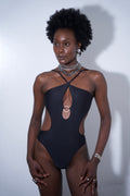 Model wearing the Stella One-piece Black swimsuit featuring cutout details and high-cut legs.
